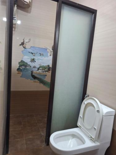 a bathroom with a toilet with a painting on the wall at Vasantham Villas in Pondicherry