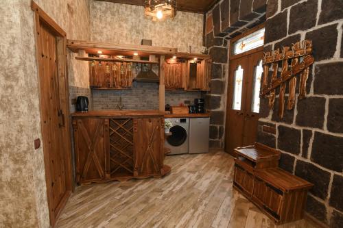 a kitchen with wooden cabinets and a brick wall at Gyumri Inn Guest House in Gyumri
