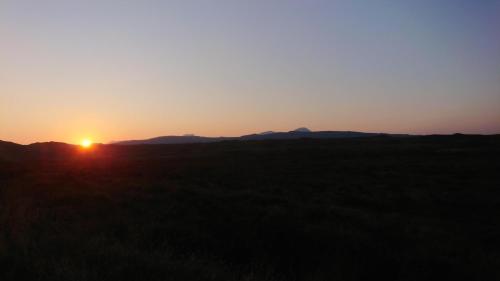 a sunset over a field with mountains in the background at Skye-Fall in Drumfearn