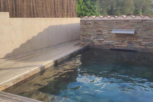 un bassin d'eau à côté d'un mur de briques dans l'établissement Tiny house avec piscine à Figari, à Figari