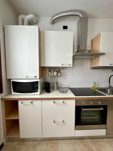 a kitchen with white cabinets and a microwave at Residence Il Mulino - 25 minutes from Venice in Mira