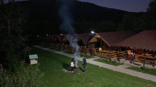 a group of people standing in the grass in front of buildings at Căsuțele Doftanei in Teşila
