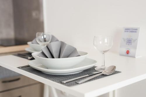 a white table with plates and wine glasses on a counter at Sobe za odmor Ema in Bilje