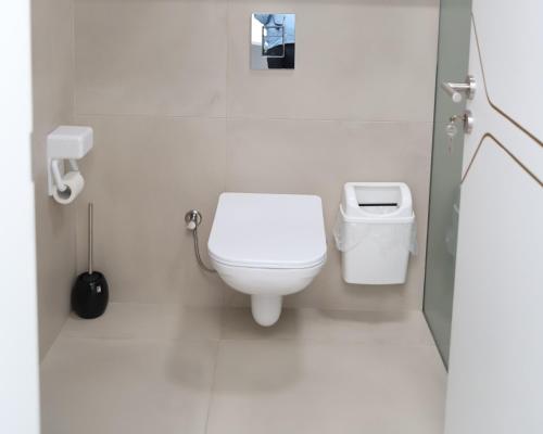 a white bathroom with a toilet and a trash can at Sky Hotel in Prizren