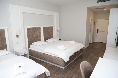 a hotel room with two beds and a chair at Sky Hotel in Prizren