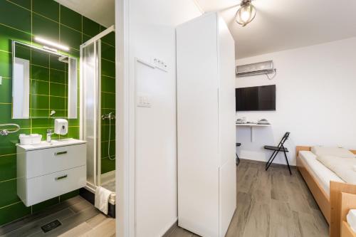 a bathroom with green tiles and a sink and a shower at Sobe za odmor Ema in Bilje