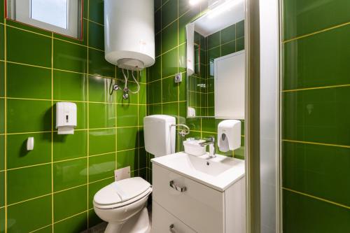 a green tiled bathroom with a toilet and a sink at Sobe za odmor Ema in Bilje