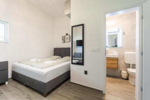 a bedroom with a bed and a bathroom with a mirror at Sobe za odmor Ema in Bilje