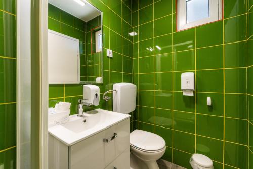 a green tiled bathroom with a toilet and a sink at Sobe za odmor Ema in Bilje