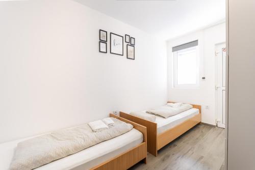 two beds in a room with white walls and wooden floors at Sobe za odmor Ema in Bilje