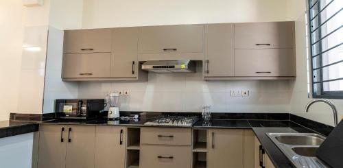 a kitchen with white cabinets and black counter tops at Leshan Luxury Villas in Diani Beach