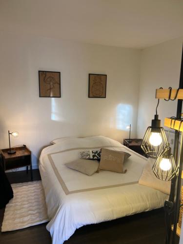 une chambre avec un grand lit blanc avec deux lampes dans l'établissement Le Nid Douillet, à Compiègne