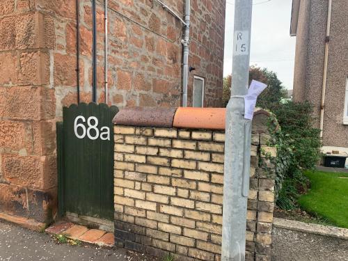 a brick wall with a sign on the side of a building at Garden Gate Upper Apartment in Prestwick