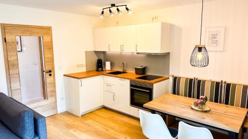 a kitchen with a wooden table and a kitchen with white cabinets at Ferienwohnung Repetal in Attendorn
