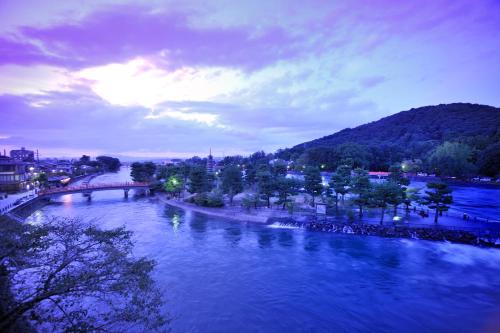 a view of a river with a bridge and a city at Hanayashiki Ukifune-en in Uji