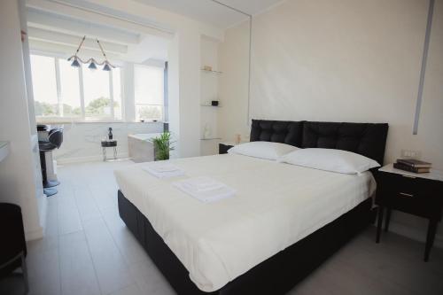 a bedroom with a large white bed and a bathroom at Suite La PerlaNera- TorreCanne in Torre Canne