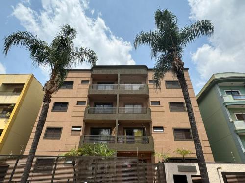 two palm trees in front of a building at Apto próximo Ribeirão Shopping in Ribeirão Preto