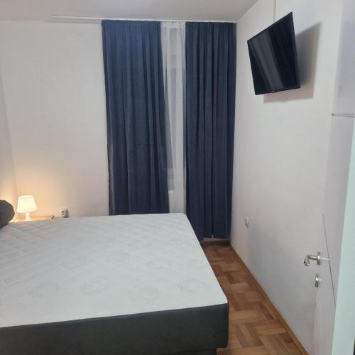 a bedroom with a bed and a television on the wall at ONLY 4 YOU apartment in Niš