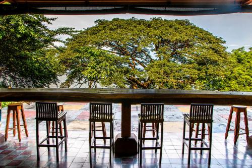 three chairs and a bar with trees in the background at Casa Hacienda El Menco in Rivas
