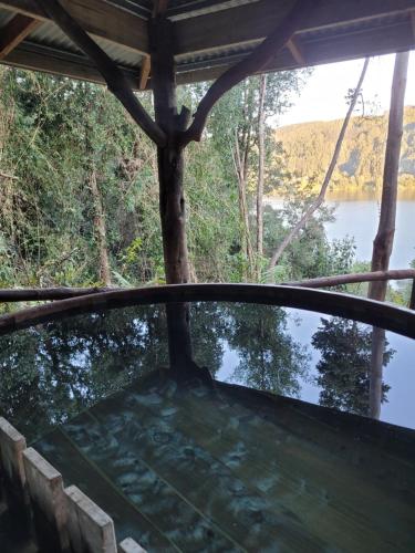 a view from the inside of a screened in porch overlooking a lake at La Rueda del Chucao in Valdivia