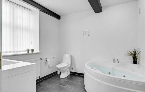 a white bathroom with a tub and a toilet at Holiday Home Engsvinget Højer X in Vrågård