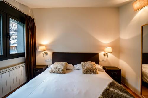 a bedroom with a large white bed with two pillows at Apartaments Superior in El Tarter