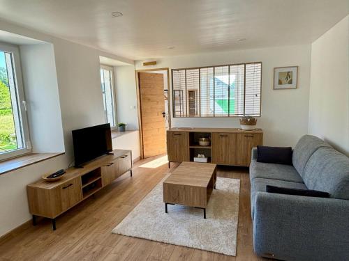 a living room with a couch and a tv at Appartement neuf 2 pièces 43m2 "Les Cimes" in La Chaux Neuve