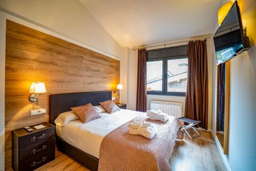 a hotel room with a bed and a flat screen tv at Apartaments Superior in El Tarter