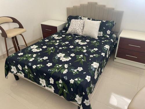 a bedroom with a bed with a black and white floral bedspread at Habitación económica in Santiago de los Caballeros