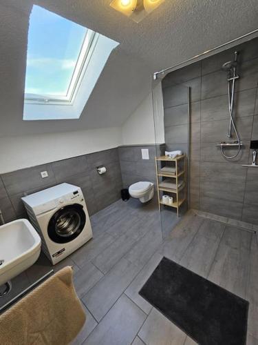 a bathroom with a shower and a washing machine at Moderne Ferienwohnung Attendorn in Attendorn