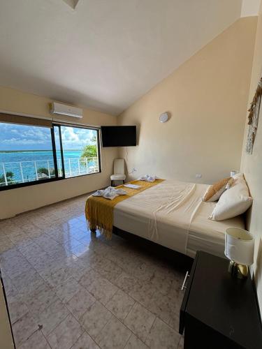 a bedroom with a large bed with a view of the ocean at Casa Sirena - Habitaciones a orilla de la Laguna y Cenote Esmeralda in Bacalar
