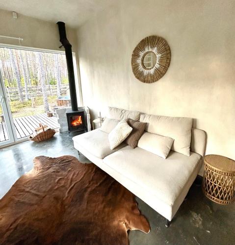 a living room with a white couch and a fireplace at Domek lubiana180 WABI SABI w lesie jacuzzi sauna kominek - drewno w cenie pobytu - nad jeziorem Kaszuby pieski tylko do 10kg za dodatkową opłatą in Łubiana