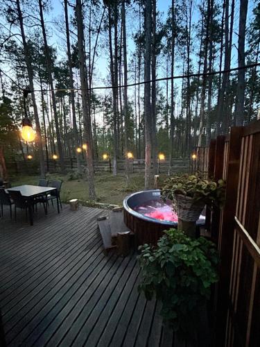 a hot tub sitting on a deck with a table at Domek lubiana180 WABI SABI w lesie jacuzzi sauna kominek - drewno w cenie pobytu - nad jeziorem Kaszuby pieski tylko do 10kg za dodatkową opłatą in Łubiana