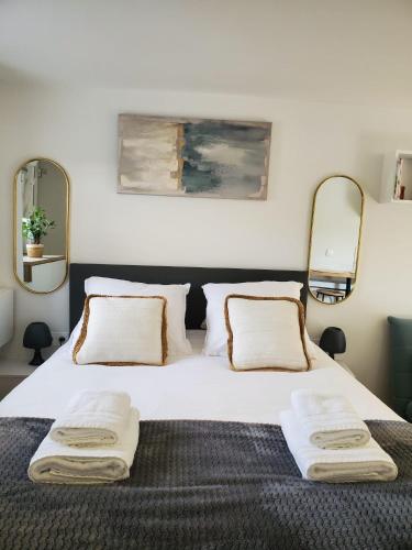 a bedroom with a large white bed with two mirrors at annecy poisy Studio a 9 minutes du lac Annecy in Poisy