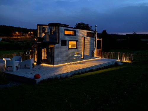 una pequeña casa con terraza por la noche en Tiny Cosy, en Bastogne