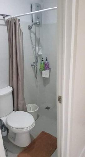 a white bathroom with a toilet and a shower at Skymagz 314 at Cityscape Residences in Bacolod