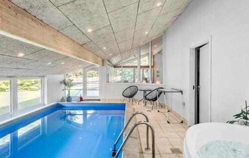 a large swimming pool in a room with a house at Nice Home In Væggerløse With Sauna in Marielyst