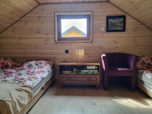 a bedroom with a bed and a chair in a cabin at Mazury Przyjazny Dom w Leleszkach z gorącą balią in Leleszki