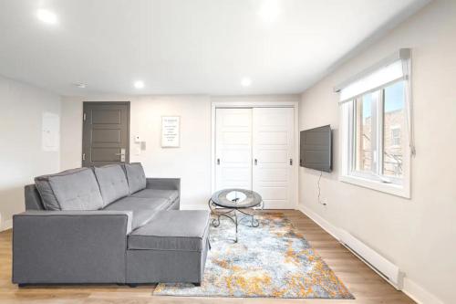 a living room with a gray couch and a window at Fancy 3 BDR in Heart of Plateau B in Montréal
