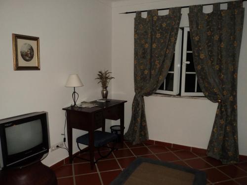 a room with a desk and a television and a window at Alojamento Pero Rodrigues in Alandroal