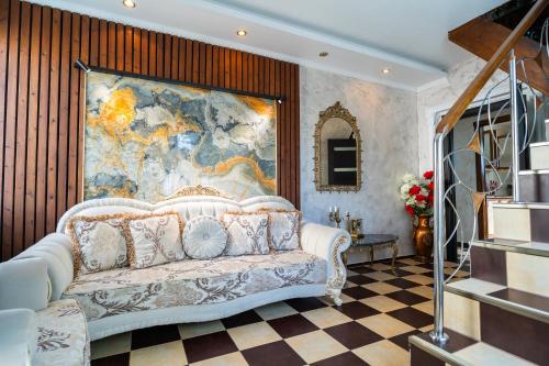 a living room with a white couch and a large painting at High-end 3BR Apartment - Private Garden, Terrace & BBQ in Bucharest