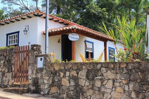 a small white house behind a stone wall at Casa Trindade in Tiradentes