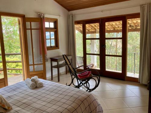 a bedroom with a bed and a table and windows at Chalés de Valfena in São Francisco Xavier