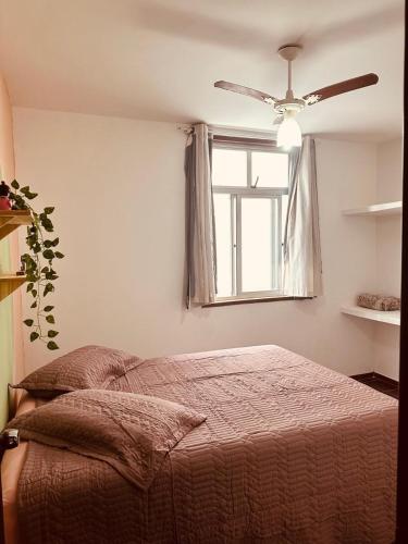 a bedroom with a bed with a ceiling fan and a window at RAIO DE LUZ GUARAPARI BEACH in Guarapari