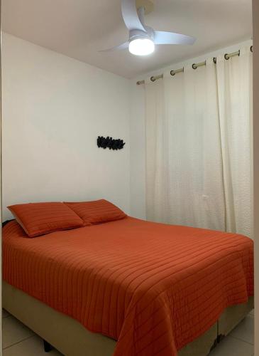 a bedroom with a bed with an orange blanket at Apartamento completo no Guarujá in Guarujá