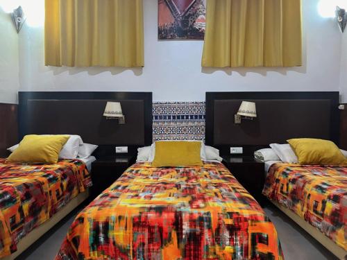 a room with two beds with colorful sheets at Riad Le Lieu in Tiznit