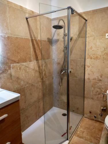 une douche avec une porte vitrée dans une salle de bain dans l'établissement Charmant petit studio, à La Grande Motte
