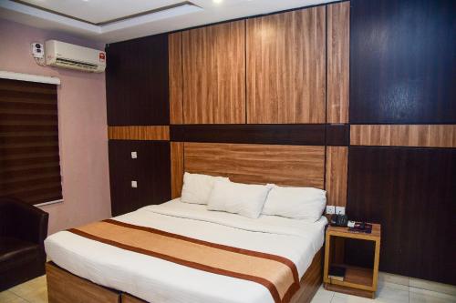 a bedroom with a large bed with a wooden headboard at Hotel De Alommah Kubwa Abuja in Abuja