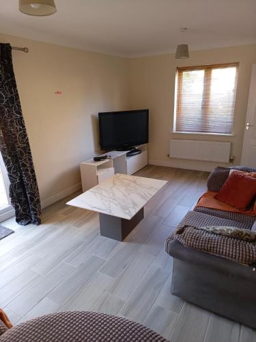 a living room with a flat screen tv and a couch at The Iris house is close to city centre and is ideal for tourists, visiting family members or work related activities including contractors in Peterborough