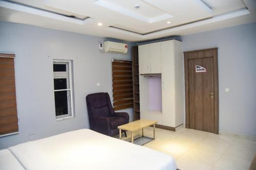 a bedroom with a bed and a chair at Hotel De Alommah Kubwa Abuja in Abuja